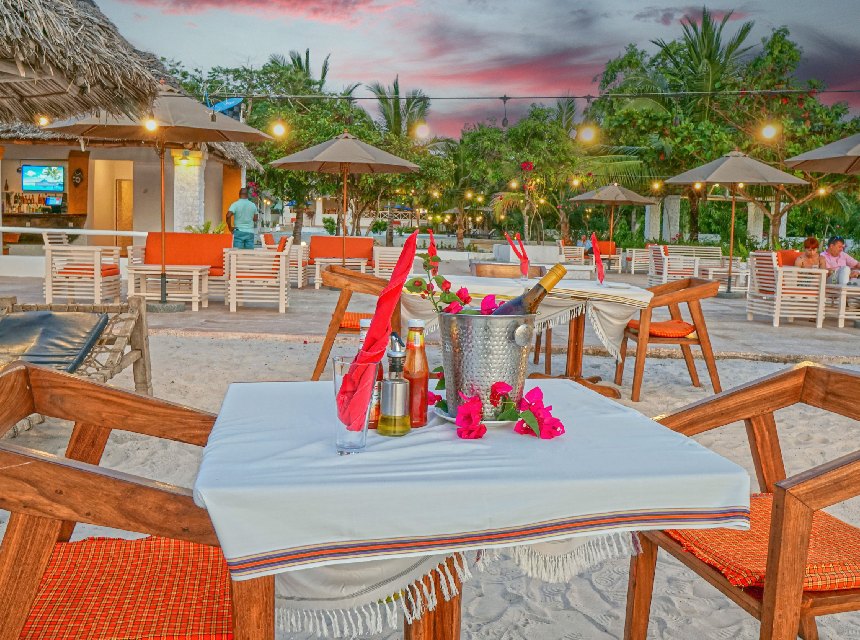 Beach restaurant at dusk with candle-lit tables on the sand