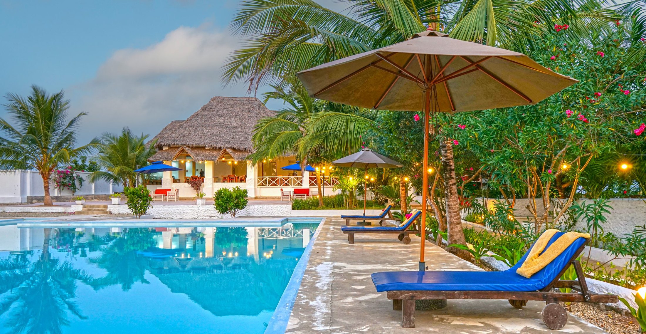 The infinity pool at golden hour with sun loungers facing the ocean