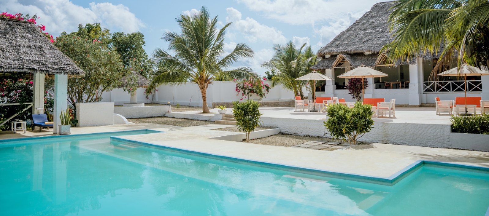 Sun loungers beside the pool with the makuti-roofed restaurant behind